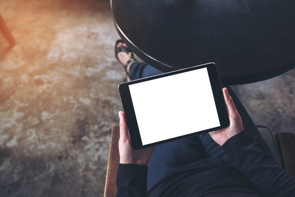 Top view mockup image of a woman sitting cross legged and holding black tablet pc with blank white desktop screen  - Photo, Image
