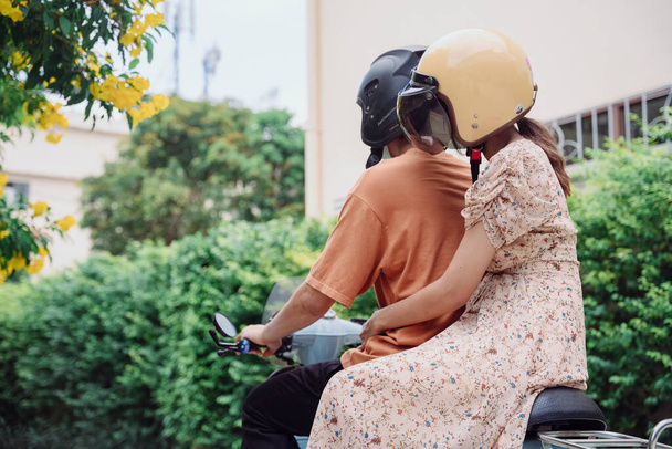 Ταξί μοτοσικλετιστής και γυναίκα πελάτης στο δρόμο. Ένα ταξί μοτοσικλέτας μεταφέρει έναν επιβάτη σε ένα δρόμο της πόλης. - Φωτογραφία, εικόνα