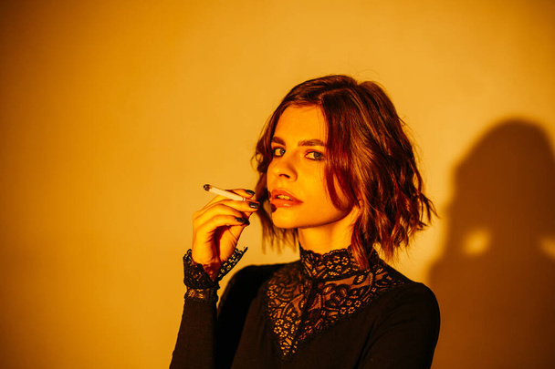 Woman with a cigarette, on a yellow background - Foto, Imagem
