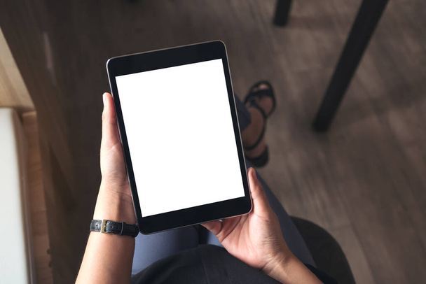 Draufsicht Attrappe Bild einer Frau sitzt im Schneidersitz und hält schwarzen Tablet-PC mit leeren weißen Desktop-Bildschirm  - Foto, Bild