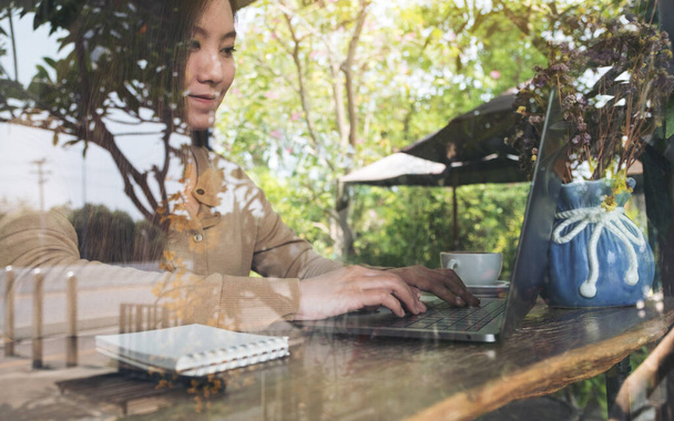 Lähikuva kuva liiketoiminnan nainen työskentelee ja kirjoittamalla kannettavan näppäimistön puinen pöytä kahvilassa  - Valokuva, kuva