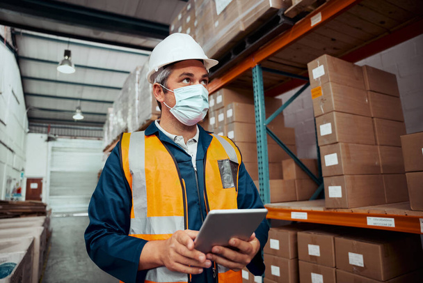 Portrait of a male worker working at warehouse with digital tablet wearing safety mask at storehouse - coronavirus  - Zdjęcie, obraz