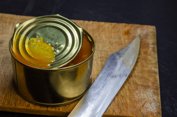 Canned food, shelf life food concept. An open tin can with food and a knife close-up. Selective focus. - Photo, Image