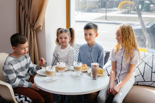 A large friendly company of children celebrate the holiday in a cafe with a delicious dessert. The day of the birth - Fotografie, Obrázek