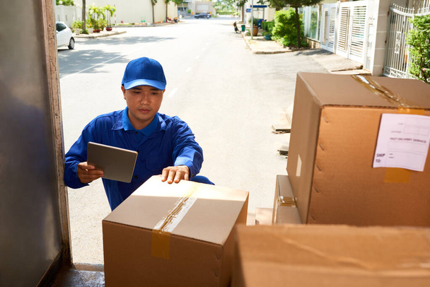 Servicio de entrega trabajador comprobar la información en el ordenador tableta al cargar camión con cajas - Foto, imagen