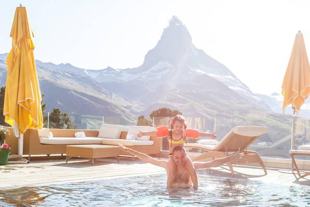 Family In Swimming Pool In Mountains. Beautiful outdoor scene in Swiss Alps, Switzerland, Europe. - Photo, Image