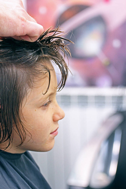glücklicher Junge sieht in gehacktem Friseurladen vor Haarschnitt auf rosa Hintergrund aus - Foto, Bild