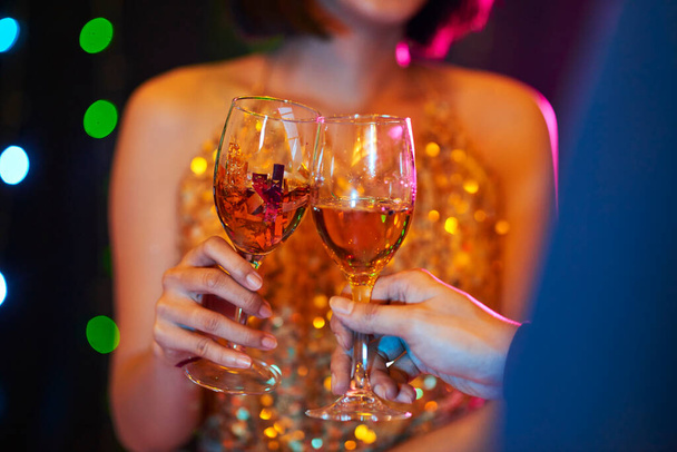 Nahaufnahme eines jungen Paares, das sich auf einer nächtlichen Party unterhält und Wein trinkt - Foto, Bild