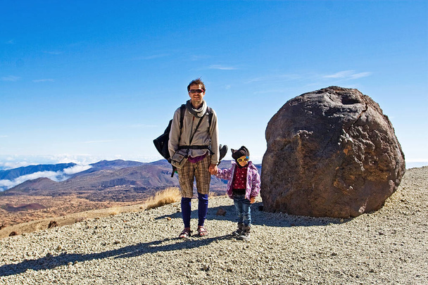 feliz pequeño escalador con papá camina a lo largo del camino hacia el volcán Teide, huevo de piedra de Tenerife, fondo natural, paisaje de montaña - Foto, imagen