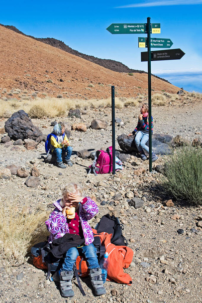 pequeños escaladores felices en la rampa antes de subir al volcán del Teide, comer sándwiches, paisaje de montaña, España - Foto, Imagen
