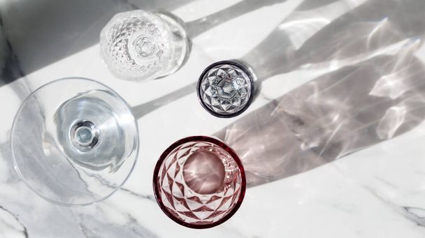 Variety of empty glasses diffrent colors on gray stone background with hard shadows and sun glare. organic shadows. ,sober concept. trendy shadows and hard sunlight reflection,top view - Photo, Image