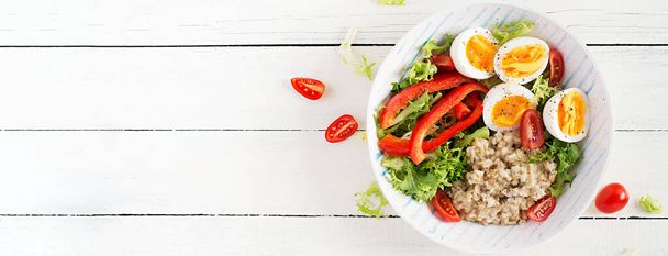 Pequeno-almoço mingau de aveia com ervas verdes, ovo cozido, tomates e páprica. Comida saudável e equilibrada. Visão superior, sobrecarga, banner - Foto, Imagem