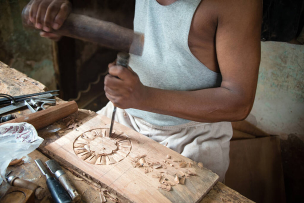 Detalle del carpintero creando ornamentos sobre tabla de madera utilizando herramientas manuales tradicionales - Foto, imagen