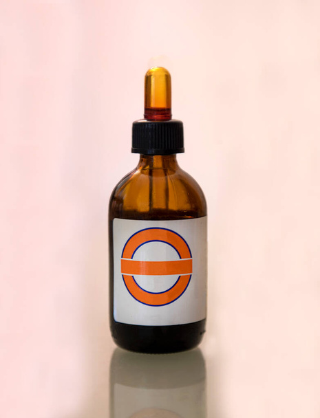 Pharmazeutisches Produkt in Flasche mit Flüssigkeit für Erste Hilfe oder andere Anwendungen in rosa isoliertem Hintergrund - Foto, Bild