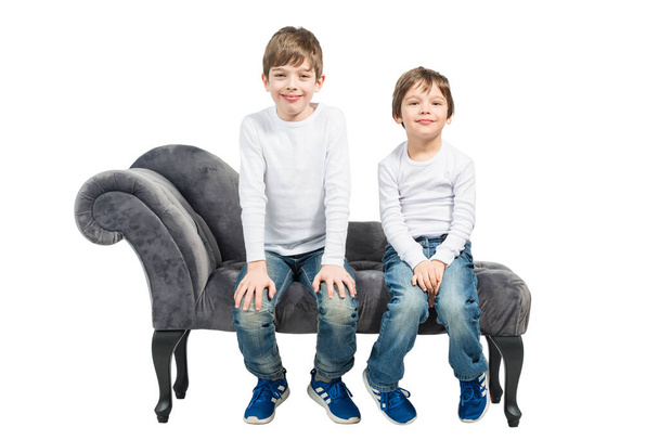 Портрет двох молодих хлопчиків, що сидять на дивані, ізольовані на білому тлі
 - Фото, зображення