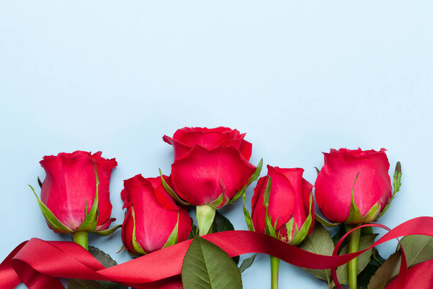 Valentijnsdag wenskaart met rode roos bloemen boeket op blauwe achtergrond. Bovenaanzicht plat lag met ruimte voor uw groeten - Foto, afbeelding