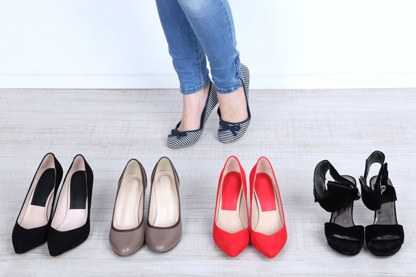 Chica elige zapatos en la habitación sobre fondo gris
 - Foto, imagen