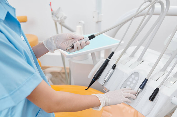 Ausgeschnittenes Bild einer Zahnärztin in Gummihandschuhen, die Handstücke überprüft, die in der Zahnmedizin verwendet werden - Foto, Bild