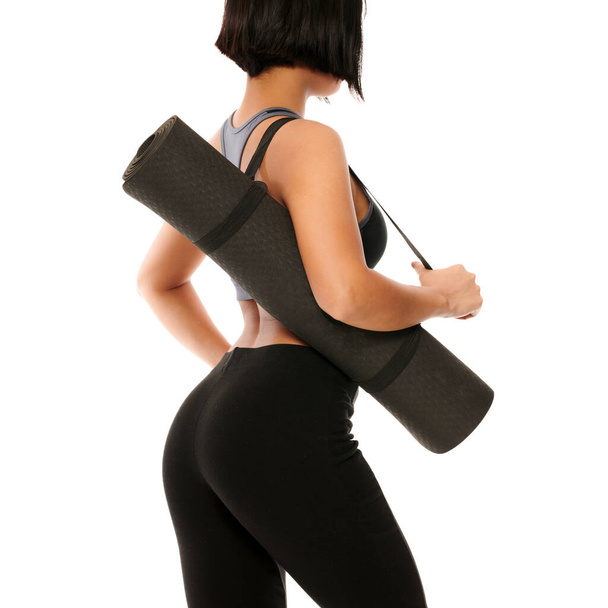 A young female in sports wear holding a black yoga mat after exercise - Φωτογραφία, εικόνα
