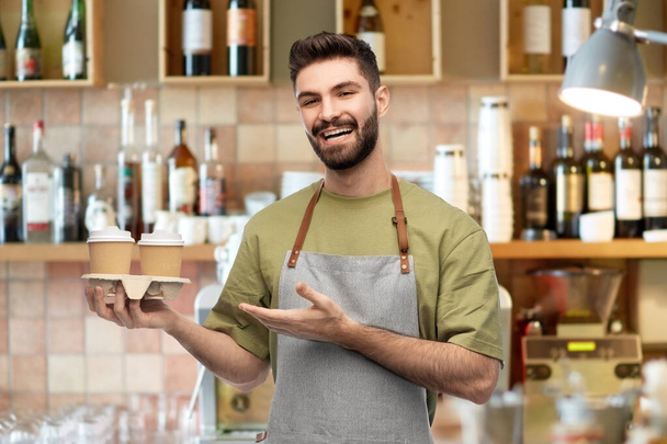 счастливый улыбающийся бармен в фартуке с кофе на вынос - Фото, изображение