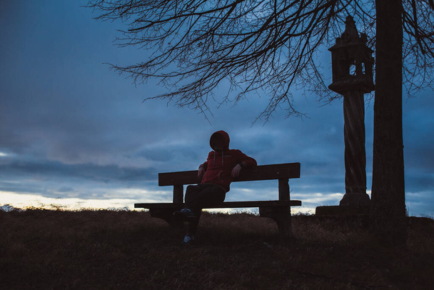 silhouette of a mysterious hacker, lonely anonymous man sitting on a bench  - Photo, Image
