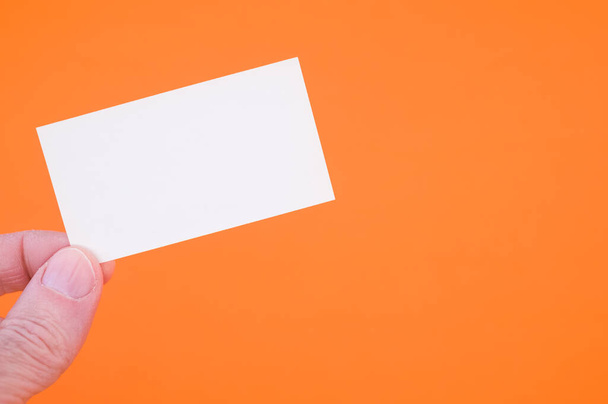 A closeup shot of a person holding a blank paper on an orange background - Foto, Bild
