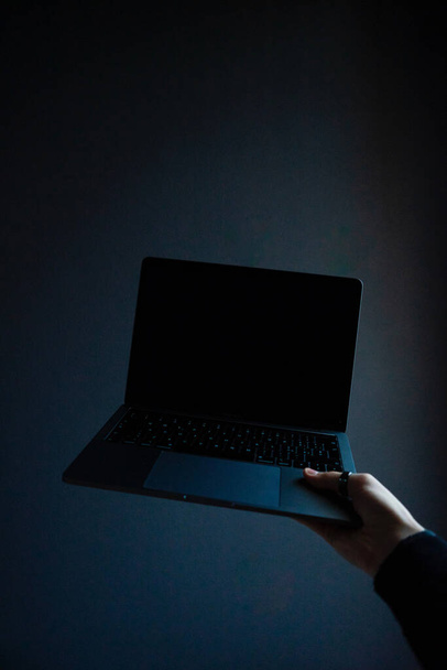 A vertical shot of a person holding a modern laptop - Zdjęcie, obraz