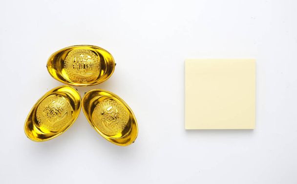 Egy kép jegyzetfüzet és arany ingot vagy "jüan bao" írva kínaiul a jólét elszigetelt fehér háttér. A jólét koncepciójának keresése - Fotó, kép