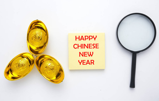 Obrázek lupy, Šťastný čínský Nový rok na notepadu a zlatý ingot nebo "juan bao" napsané v čínštině pro prosperitu na izolovaném bílém pozadí. Hledám koncept prosperity - Fotografie, Obrázek