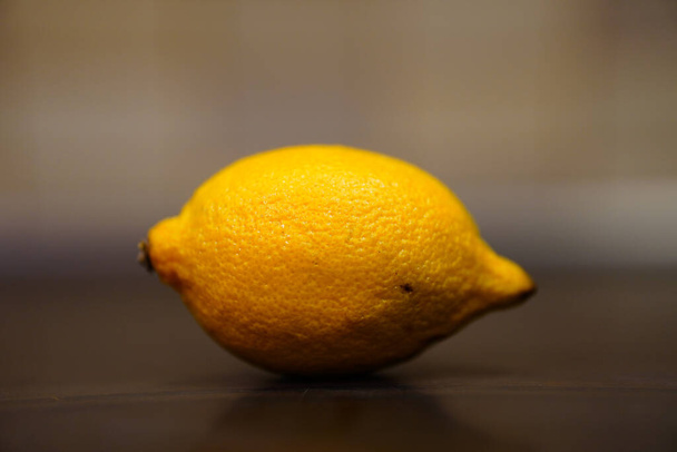 A selective focus shot of a lemon on a wooden table - Foto, Bild