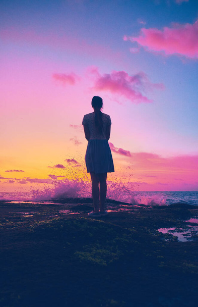 Silhouette of a girl on the shores of the Indian Ocean during a saturated sunset - 写真・画像