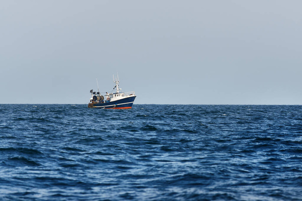 Kleine vissersboot varen in een open Middellandse Zee, close-up. Uitzicht vanaf het jacht. Vrijetijdsbesteding, sport en recreatie, voedingsmiddelenindustrie, ambachtelijke nijverheid, begrip milieuschade - Foto, afbeelding