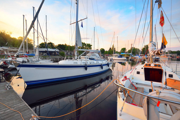 Élégants et modernes voiliers modernes (à louer) amarrés à une jetée dans une marina de yacht au coucher du soleil. Transport, croisière, loisirs, sport et loisirs thème. Suède - Photo, image