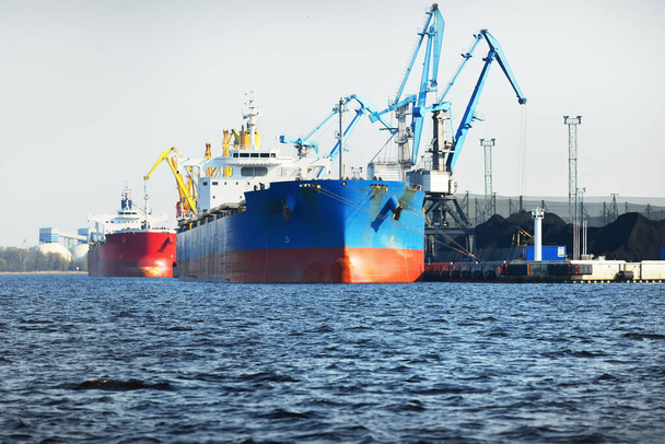 Μεγάλο πλοίο μεταφοράς χύδην φορτίου (φορτηγό πλοίο) στον τερματικό σταθμό άνθρακα, κοντινό πλάνο. Οι γερανοί στο βάθος. Νήσος Krievu, Ρίγα, Λετονία. Μεταφορές εμπορευμάτων, παραγωγή καυσίμων και ηλεκτρικής ενέργειας, περιβαλλοντικές ζημιές - Φωτογραφία, εικόνα