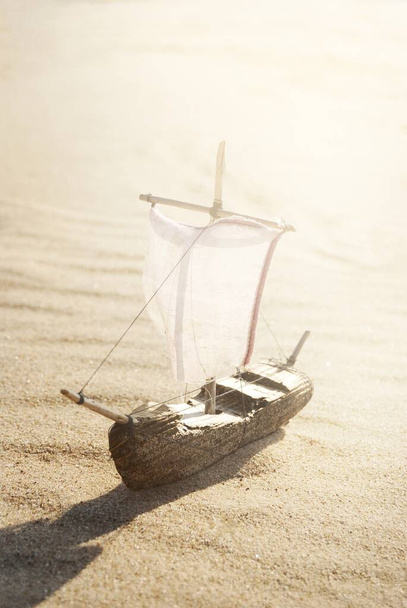 Einfaches Modell eines großen Schiffes aus Holz, Spielzeug für Kinder, im Hintergrund Sanddünen. Minimalismus, Kunst, Zero-Waste-Konzept, Handarbeit, Design, Umweltschutz Thema - Foto, Bild