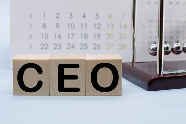 CEO - chief executive officer - acronym on wooden cubes, Newton's cradle and calculator. Business concept - Photo, Image