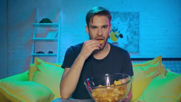 Hombre comiendo patatas fritas y viendo el partido de fútbol en casa  - Metraje, vídeo