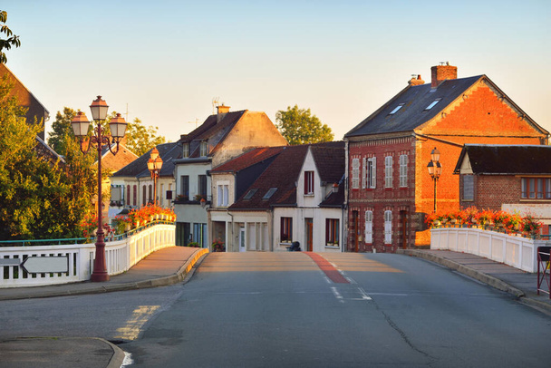 Pusta ulica przez małą wioskę. Dom rustykalny i zbliżenie mostu. Normandia, Francja. Cele podróży, zabytki, zwiedzanie, turystyka, tradycyjna architektura. Widok panoramiczny, krajobraz miejski - Zdjęcie, obraz