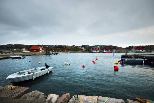 Motorboten, zeil- en vissersboten afgemeerd aan een pier in een klein dorpje in Rogaland, Noorwegen. Traditionele architectuur. Dramatische avondlucht. Reisbestemmingen, vakanties, vrijetijdsbesteding - Foto, afbeelding