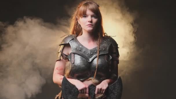 Atmospheric portrait of a scandinavian female barbarian with axe in dark and smokey background - Footage, Video