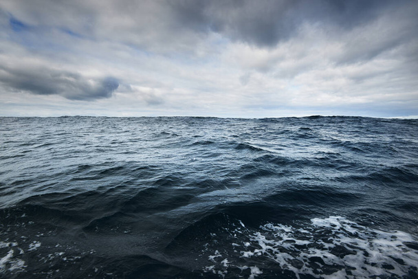 Ein Blick von einem Segelboot auf die stürmische Nordsee. Bewölkter blauer Himmel, der sich im Wasser spiegelt. Dramatische Wolkenlandschaft. Rogaland, Norwegen. Freizeitaktivitäten, Umweltschutzkonzepte - Foto, Bild
