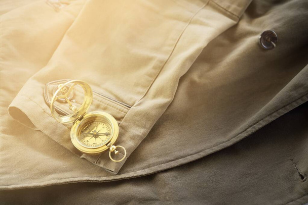 Brújula dorada antigua (reloj de sol) y el viejo abrigo marrón de cerca. Bodegón vintage. Vela, accesorios de viaje, arte conceptual, coleccionismo, ropa, equipo, recursos gráficos - Foto, imagen