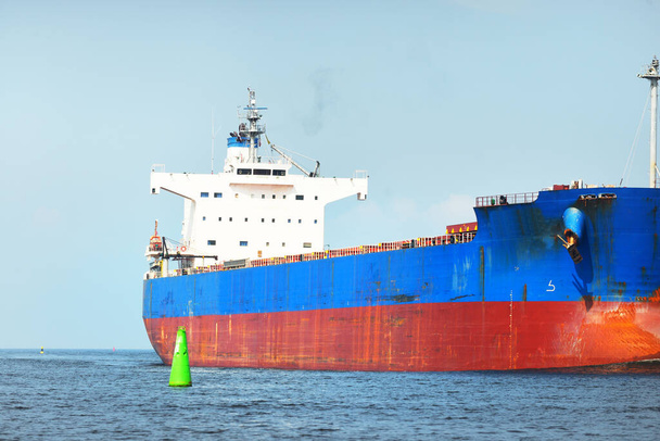 Μεγάλο μπλε πλοίο μεταφοράς χύδην φορτίου (πλοίο) που πλέει στη Βαλτική θάλασσα προς το λιμάνι της Ρίγας, Λετονία. Θέα από το γιοτ. Γενικό φορτίο. Διεθνείς επικοινωνίες, εφοδιαστική, βιομηχανία, εμπορευματικές μεταφορές - Φωτογραφία, εικόνα