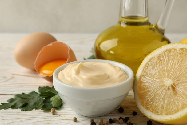 Bowl with mayonnaise and ingredients for cooking on wooden background - Photo, Image