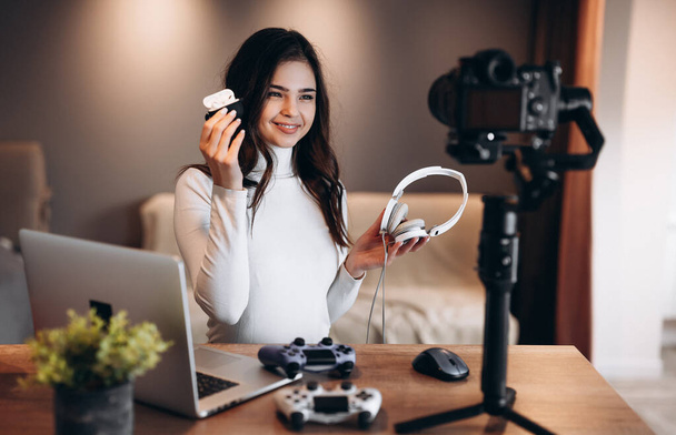 Pretty blogger woman is filming and showing her preference in headphones for video games. Influencer young woman live streaming. - Photo, Image