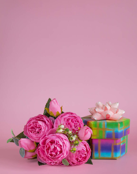 Gift box and bouquet of flowers on pink background. The concept of congratulations for Valentine's Day, birthday, International Women's day and other holidays. Vertical banner. Copy space - Foto, imagen