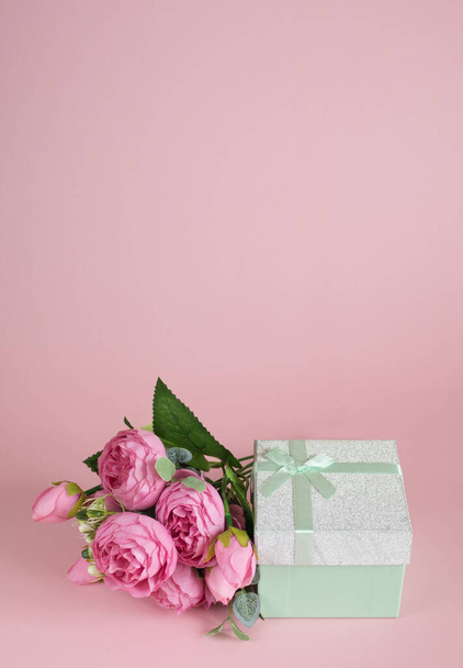 Gift box and bouquet of flowers on pink background. The concept of congratulations for Valentine's Day, birthday, International Women's day and other holidays. Vertical banner. Copy space - Φωτογραφία, εικόνα