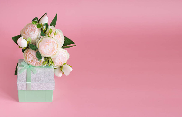 Gift box and bouquet of flowers on pink background. The concept of congratulations for Valentine's Day, birthday, International Women's day and other holidays. Copy space - 写真・画像