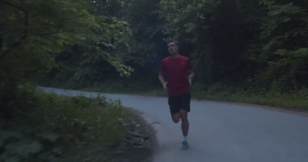 Treinamento de resistência, homem correndo sozinho na estrada da montanha, câmera siga via dolly - Filmagem, Vídeo