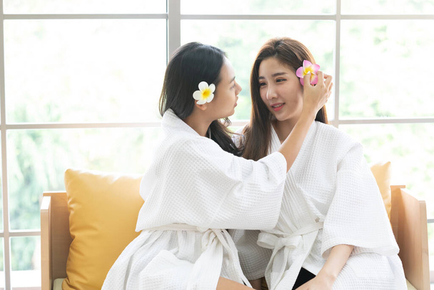 zwei junge Frauen legen im Wellness-Salon eine Blume hinter das Ohr, LGBT-Konzept - Foto, Bild
